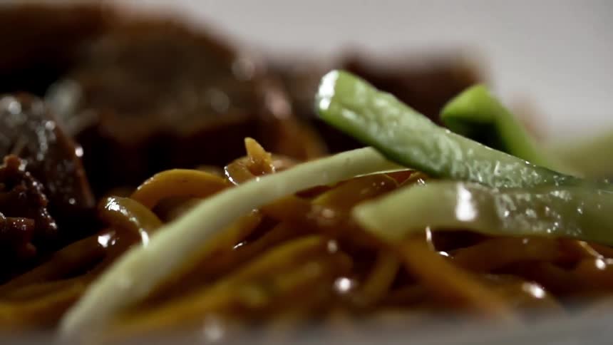 Cooked vegetables served over noodles and meat