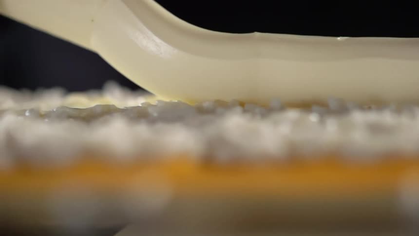Cream poured over sushi rice atop a bamboo mat