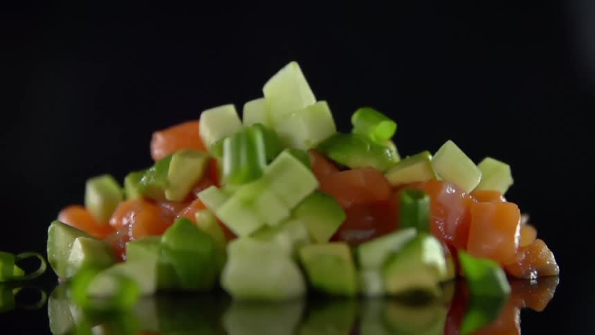 Sliced scallions falling onto a pile of diced vegetables