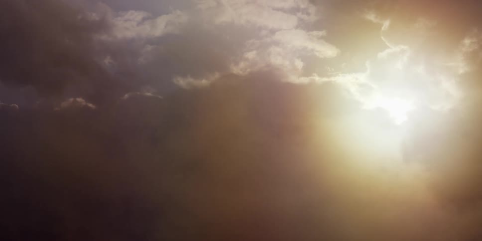 The sun is setting in a cloudy sky