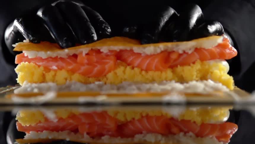 A person rolls fish and rice in to a wrap