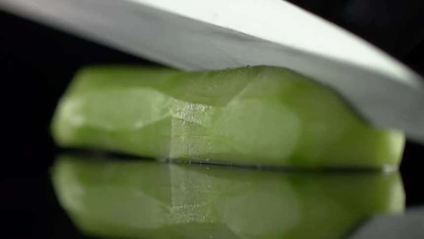 A knife slicing a cucumber
