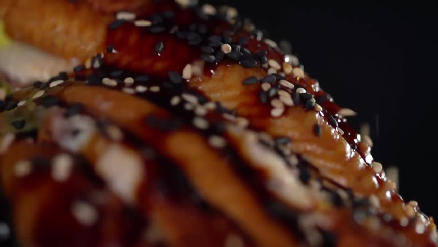 Fish being seasoned with seeds with a black background