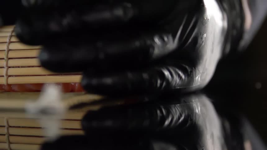 A person reaches for sushi in a sushi mat
