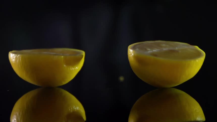 Man cuts a lemon in half on dark background