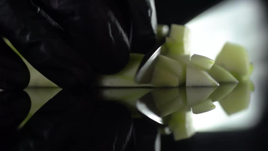 A person is slicing up food on the reflective surface