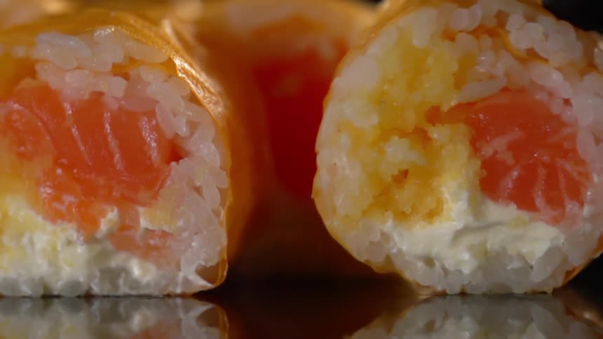 Rolls of salmon sushi rolling over a reflecting surface