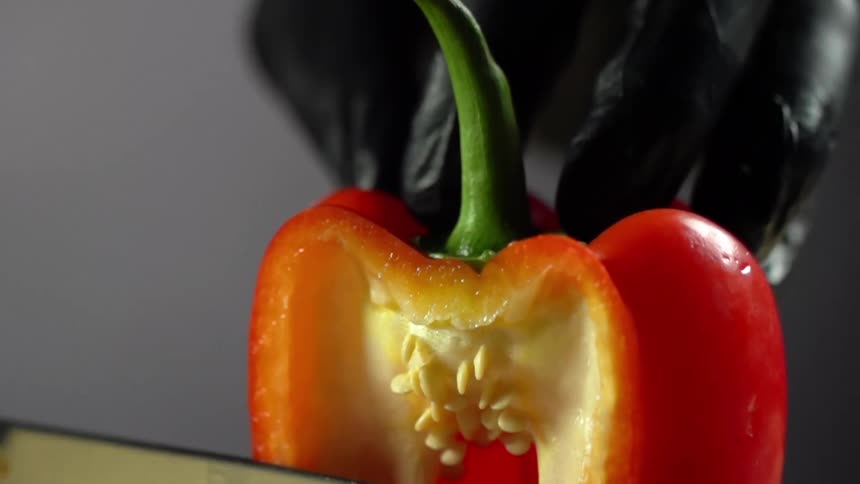A person cutting a red bell pepper