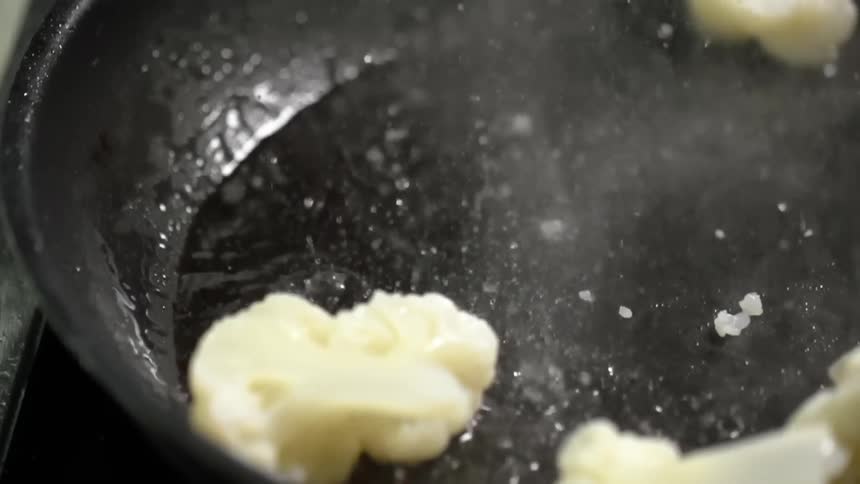 Cauliflower florets are dropped into a hot wok filled with oil