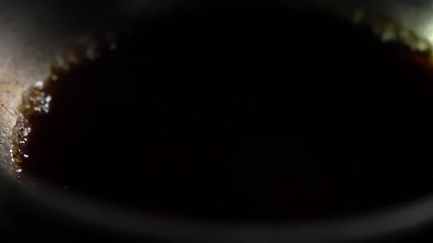 Dark thick soy sauce boils on a hot pan