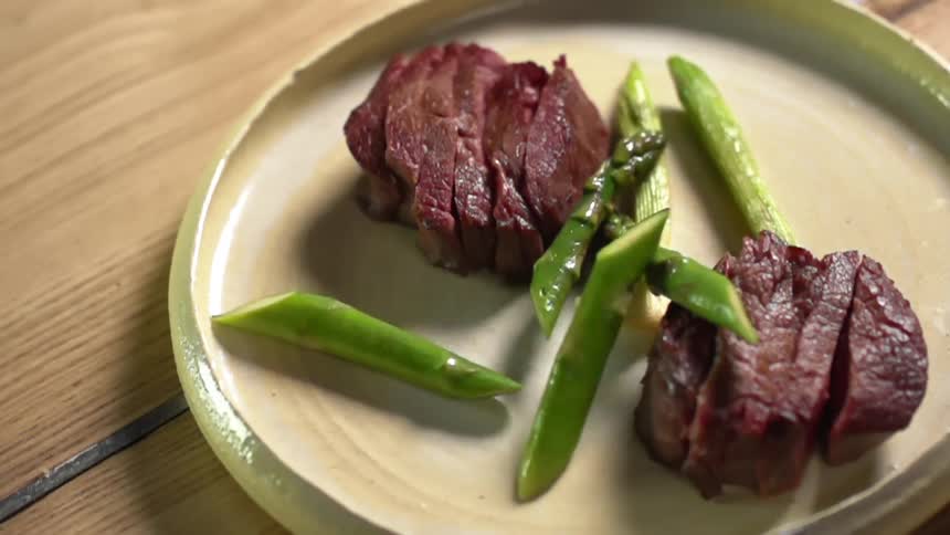 Strips of steak in a plate served with chopped asparagus