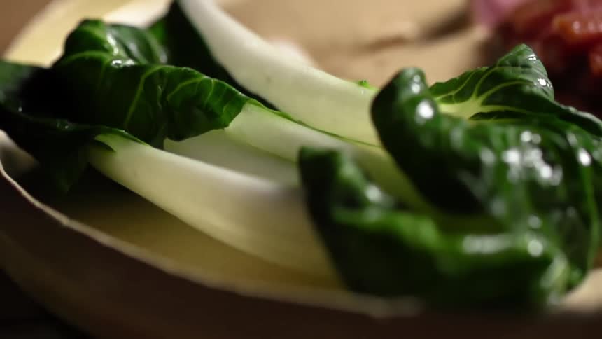 A person puts some bok choy down on a plate