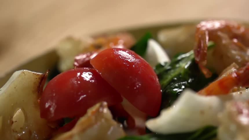 Tomatoes are dropped onto the shrimps and spinach
