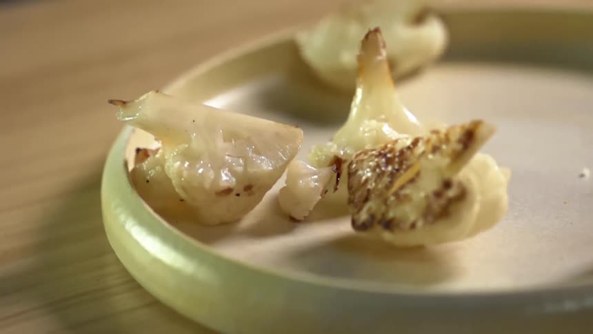 Several pieces of grilled cauliflower are poured onto a small plate