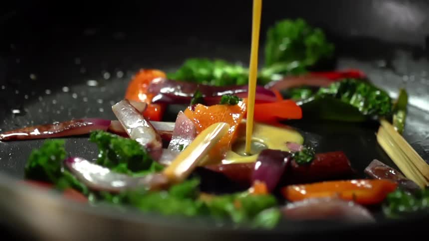 A curry sauce pours into a skillet filled with chopped vegetables