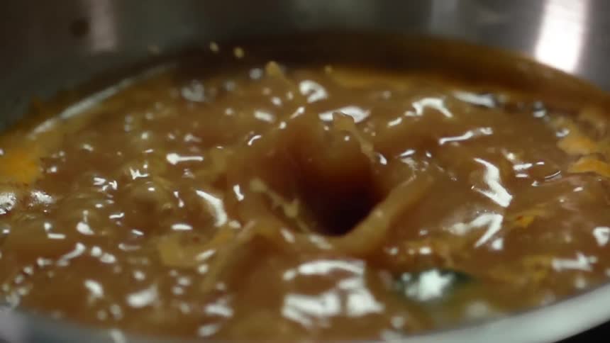 Vegetables are being put into boiling broth in a saucepan