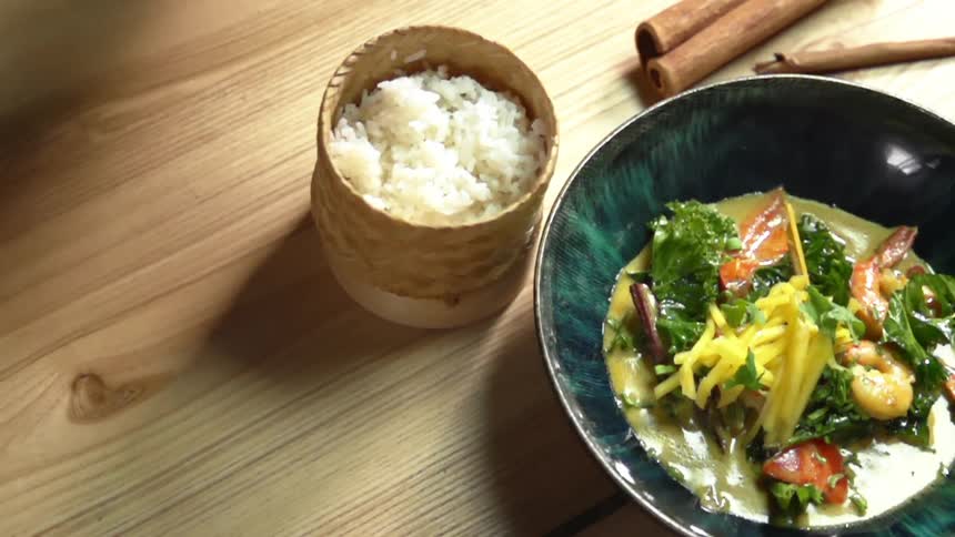 Gloved hands uncover a container of rice sitting next to a bowl of shrimp curry