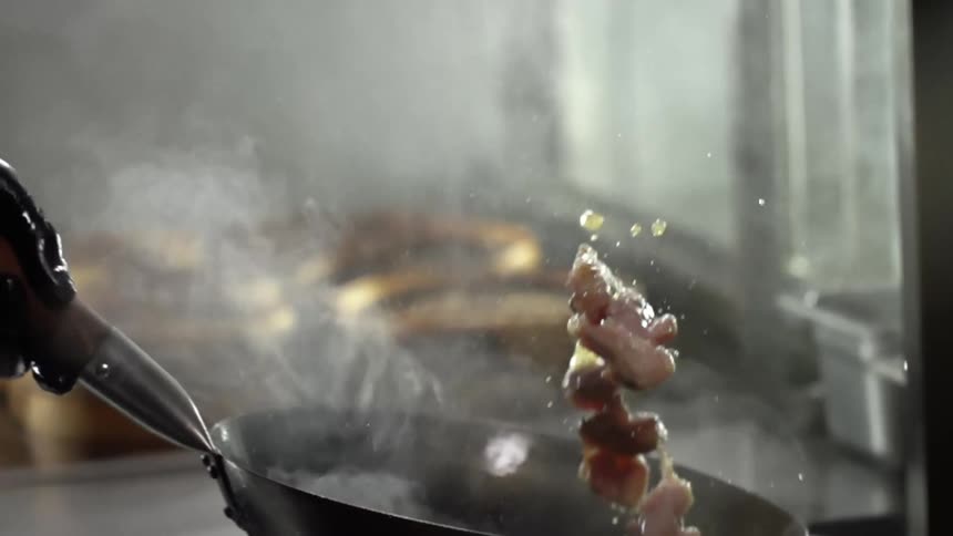 A person with black gloves tossing mushrooms in a wok with smoke coming out of it