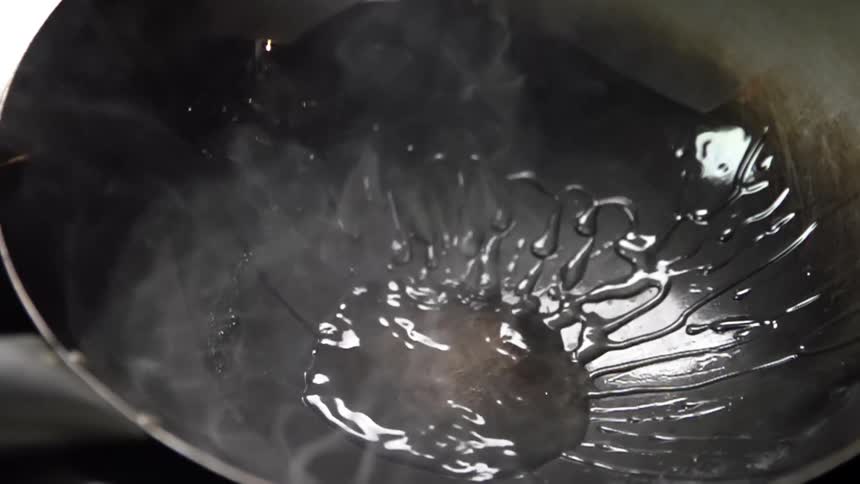 Oil is being sprayed into the hot wok