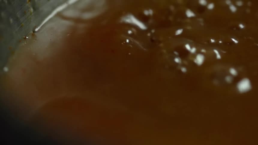 A think brown broth trickles down into a container where it splashes and bubbles