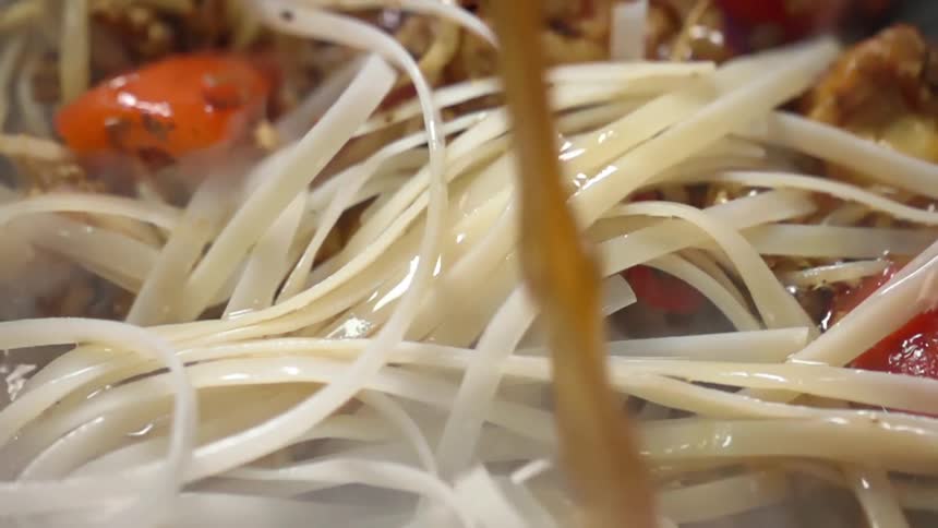 Broth pouring over noodles with vegetables