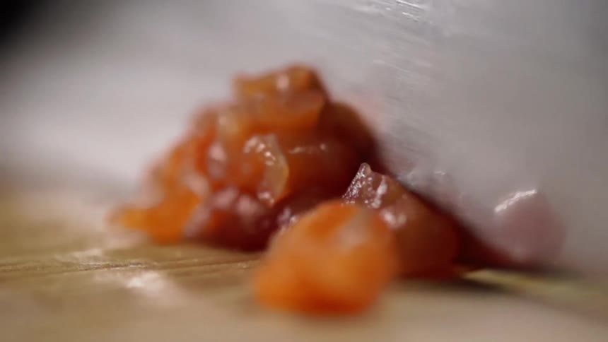 Cook slices salmon for sushi on a cutting board with a knife