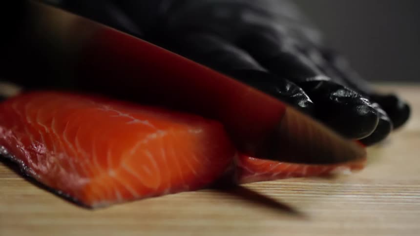 A person cuts into a piece of raw salmon