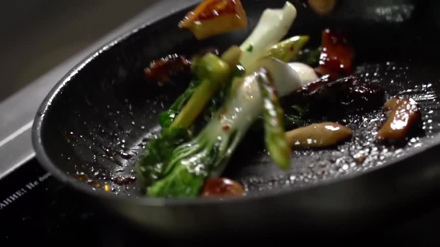 Mushrooms and bok choy being cooked in a frying pan