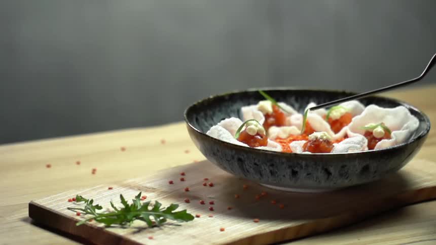 A piece of garnish is placed on the salmon in rice chips