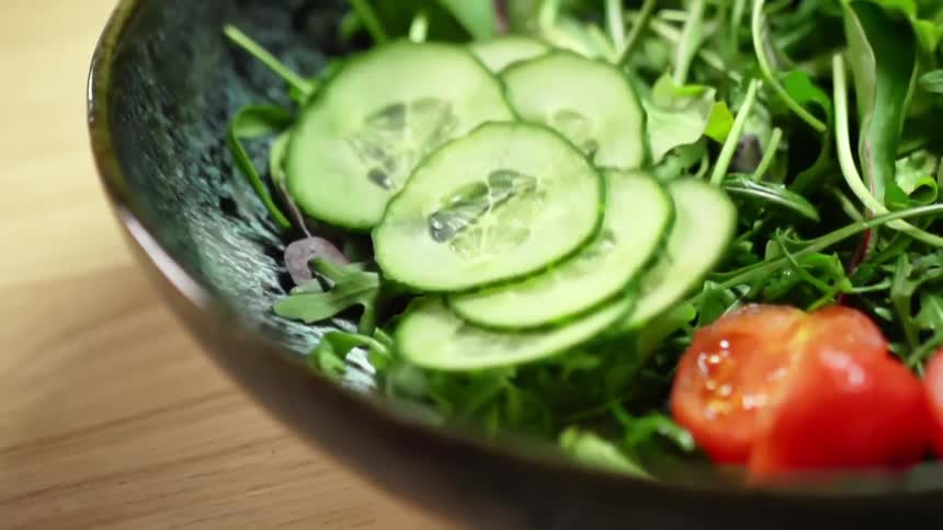 Cucumbers being placed on a salad