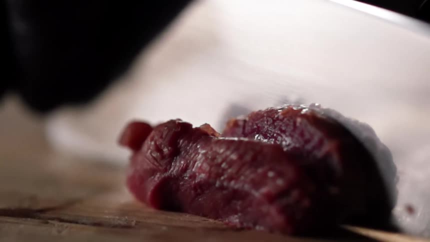 Man with black gloves cuts tuna on a cutting board