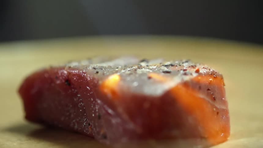 A tuna steak being torched from a flame above