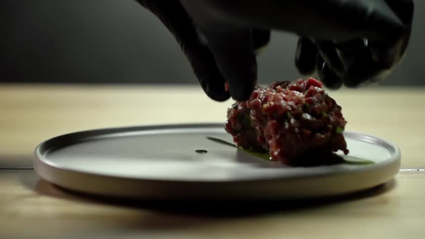 A tuna tartare is being put down on a plate