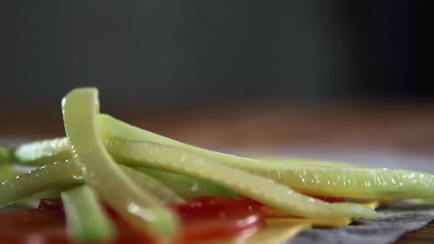 Green food slices drops onto red food sitting on a placemat