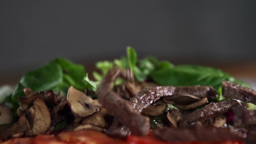 Strips of meat falling on to a bed of vegetables