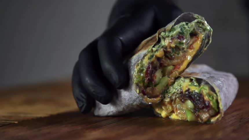 A person sets a wrap down on a wooden table