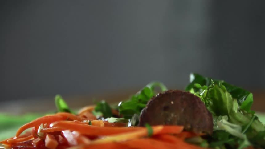 Two pieces of cooked meat drop into a vegetable salad