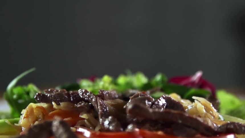 Cooked meat falls onto a plate of food