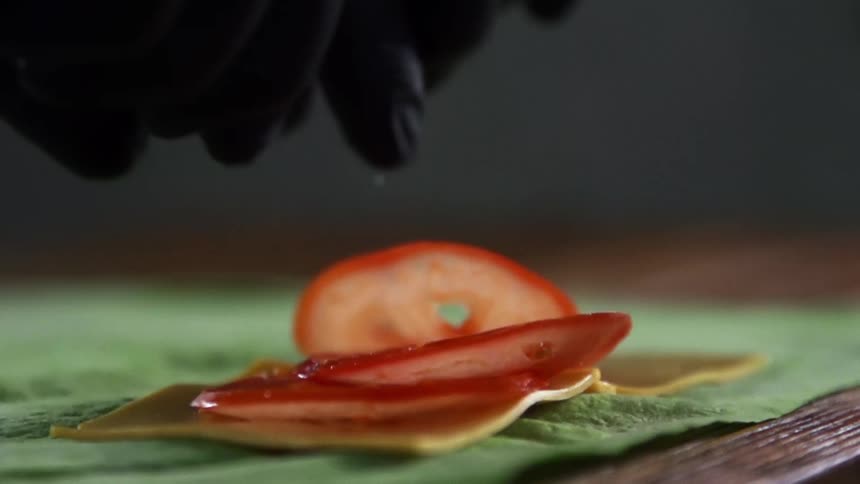 A person puts tomatoes on wrap