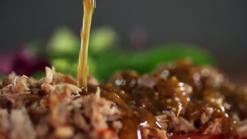 A sauce is poured over plated shredded meat