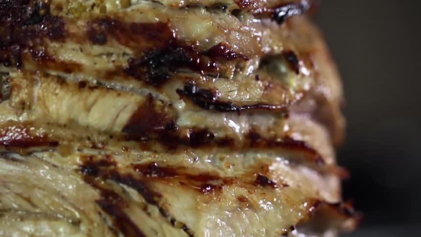 Roasted chicken is stacked on a vertical spit