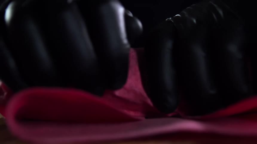 A person with gloves wrapping something on a table