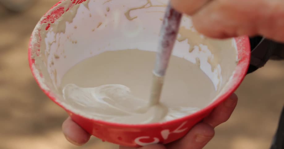 A person is stirring paint in a small bowl