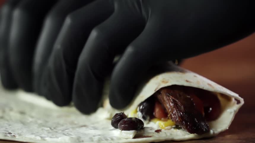 A person wrapping food in a tortilla