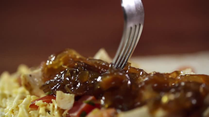 A fork slides through plated food