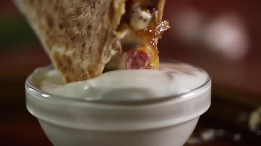 Flat bread sandwich dipping in white sauce