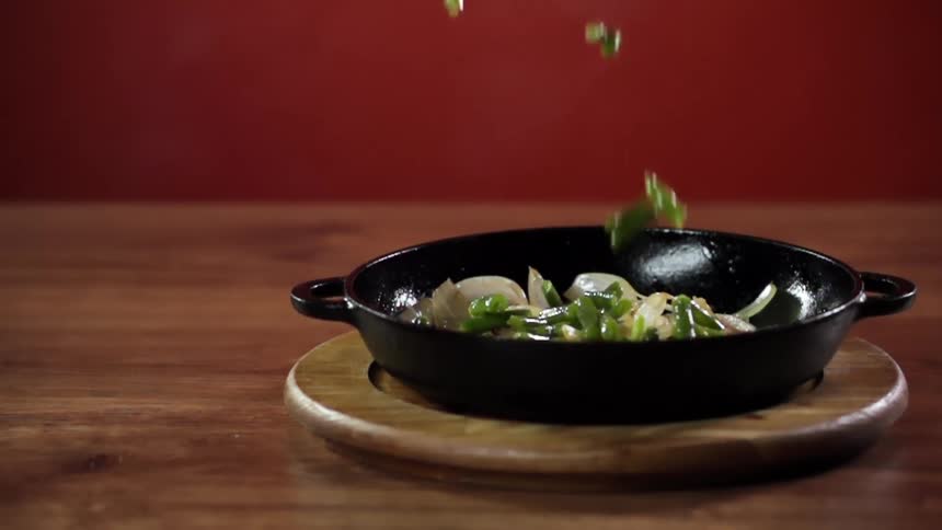 Vegetables fall into a pan on a wood table