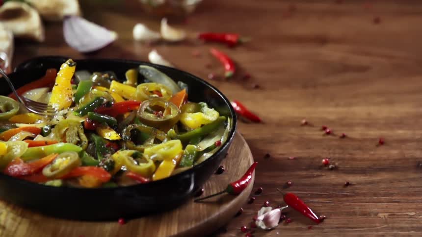 Picking up cooked vegetables from a cast iron pan with a fork