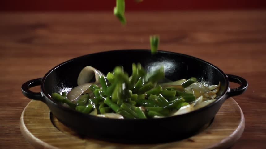 Vegetables falling into a pan with vegetables that is on a table