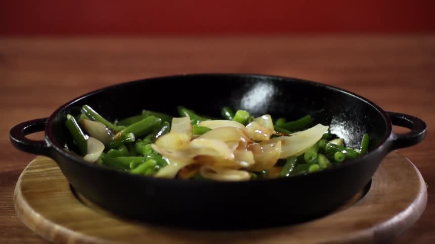 Onions falling on green beans in a pan